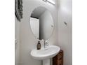 Stylish powder room with a pedestal sink, oval mirror, and neutral decor at 2681 Tuxedo Black Ct, North Las Vegas, NV 89086