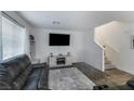 Cozy living room features a plush sofa, a large TV, and access to the staircase at 2681 Tuxedo Black Ct, North Las Vegas, NV 89086
