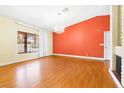 Living room with hardwood floors and an orange accent wall at 3360 Paso Andres St, Las Vegas, NV 89146