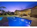 Beautiful backyard with pool, lounge chairs, dining area, and mature landscaping at dusk at 4292 Helena Cove Ct, Las Vegas, NV 89129