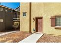 Townhome front entrance showing walkway leading to a brown front door with sidelight at 5940 Palmilla St # 9, North Las Vegas, NV 89031