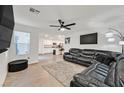 Open-concept living room with kitchen view, L-shaped sectional, and wood floors at 6867 Evening Orchid St, North Las Vegas, NV 89086