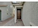 Side entrance with dark brown door and stone pathway at 7675 W Mistral Ave, Las Vegas, NV 89113