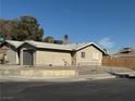Tan single story house with a grey garage door and wooden fence at 11 Page St, Las Vegas, NV 89110