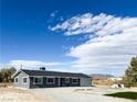 Ranch-style house with gray siding, attached garage, and desert landscaping at 1470 Sutton Dr, Pahrump, NV 89048