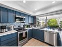 Modern kitchen with stainless steel appliances, navy cabinetry, quartz countertops, and a bright window to the backyard at 3416 Calle De Corrida, Las Vegas, NV 89102
