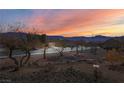 Street view showcasing desert landscaping with mountain views at sunset at 1428 Chaparral Dr, Mesquite, NV 89027