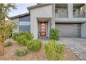 Contemporary two-story home featuring a modern front door, well-maintained landscaping, and a gray paved driveway at 1945 Canyon Highlands Dr, Henderson, NV 89052
