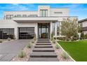 Contemporary home with manicured landscaping, glass paneled garage doors, and a walkway leading to a modern entrance at 21 Grey Owl Ct, Las Vegas, NV 89135