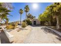 Landscaped front yard with palm trees and a long driveway leading to the house at 2179 Bridlewood Dr, Las Vegas, NV 89119