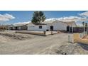 Front view of a remodeled home with a large driveway and a new fence at 2690 S Dandelion St, Pahrump, NV 89048