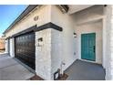 Close-up of the exterior showcasing the 3-car garage and the front door with manicured yard at 4871 Charlemagne Ave, Las Vegas, NV 89130