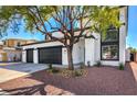 Two-story home with a three-car garage, desert landscaping and a well-manicured tree in the yard at 4871 Charlemagne Ave, Las Vegas, NV 89130