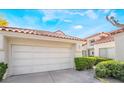 Two-car garage with a paved driveway surrounded by green landscaping and a tile roof under a blue sky at 6914 Emerald Springs Ln, Las Vegas, NV 89113