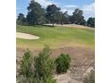 Beautiful view of a golf course with green grass, mature trees, and a sand trap at 6914 Emerald Springs Ln, Las Vegas, NV 89113