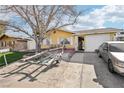 Charming single-story home with a yellow exterior, complemented by a well-maintained front yard and mature trees at 6409 Youngmont Ave, Las Vegas, NV 89103
