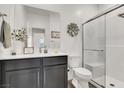 Well-lit bathroom with a single sink vanity, a walk-in shower with glass door, and neutral color palette at 3197 Vittoria Ave, Henderson, NV 89044