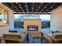 Inviting outdoor living area featuring a cozy fireplace and stylish pergola with string lights, perfect for relaxing evenings at 3372 Dalmore St, Henderson, NV 89044