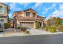 Two-story house with tan exterior, two-car garage, and landscaping at 11740 Via Esperanza Ave, Las Vegas, NV 89138