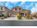 Two-story house with a tan facade and a two-car garage at 11740 Via Esperanza Ave, Las Vegas, NV 89138