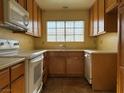 Bright kitchen with wood cabinets, white appliances, and tile flooring at 7588 Kalmalii Ave, Las Vegas, NV 89147