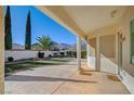 Relaxing covered patio with a view of the lush backyard featuring mature trees and manicured landscaping at 9843 Wonderful Day Dr, Las Vegas, NV 89148