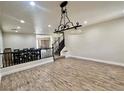 Spacious living room featuring wood-look floors, decorative lighting, and a view of the staircase and dining area at 10618 Timber Stand St, Las Vegas, NV 89183