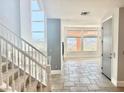 Grand entryway with tiled floor, staircase, and natural light from large windows overlooking mountain view at 24 Cerchio Alto, Henderson, NV 89011