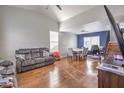 Open living space featuring wood floors, vaulted ceilings, blue accent wall, a dining area, and access to the stairs at 2727 Scotch Heather St, Las Vegas, NV 89142