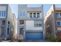 Contemporary three-story house featuring a blue garage door and sleek design at 8125 Monsoon Bay St, Las Vegas, NV 89113