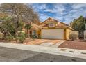 Single-story home with a two-car garage, desert landscaping, and a red tile roof, creating a warm and inviting curb appeal at 1424 Desert Hills Dr, Las Vegas, NV 89117