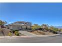 An exterior elevation of the home's entrance shows the front yard, manicured bushes and a circular driveway at 3 Chenal Pass, Henderson, NV 89052