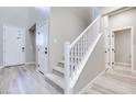 Inviting entryway featuring a staircase with white railing and light, wood-look flooring at 4341 Sunburst Spring Ave, Las Vegas, NV 89141