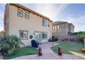 Large backyard featuring artificial grass, brick patio, and tropical foliage at 500 Via Stretto Ave, Henderson, NV 89011