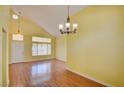 Bright living room with wood floors, chandelier, vaulted ceilings, and large window at 6086 Shadow Oak Dr, North Las Vegas, NV 89031