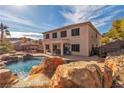 Backyard oasis featuring a sparkling pool with rock waterfall, covered patio, and lush landscaping at 790 Tossa De Mar Ave, Henderson, NV 89002