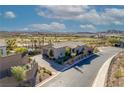 Aerial view of a single-story home with a charming brick driveway surrounded by mature landscaping and lush green golf course views at 91 Alta Cascata Pl, Henderson, NV 89011