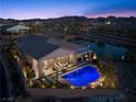 Aerial view of a backyard with a sparkling pool, cozy seating area, and scenic mountain views at twilight at 91 Alta Cascata Pl, Henderson, NV 89011