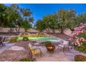 Beautiful backyard oasis with a pool, waterfall feature, firepit, and lush landscaping at 10528 Meadow Mist Ave, Las Vegas, NV 89135