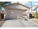 A spacious two-car garage with concrete driveway and desert landscaping at 10765 Muscari Way, Las Vegas, NV 89141