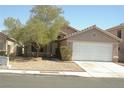 Tan single story home with low maintenance yard and white two car garage door at 108 Zenith Point Ave, North Las Vegas, NV 89032