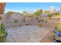 Beautiful backyard with desert landscaping, stone wall, and a custom tiled patio for relaxing and entertaining at 11908 Love Orchid Ln, Las Vegas, NV 89138