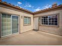 A cozy corner patio featuring a sliding glass door, window, and entry door with desert-toned stucco and a tile roof at 1851 Hillpointe Rd # 2124, Henderson, NV 89074