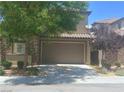 Attached two-car garage with a neutral color, providing ample parking and storage space, complemented by mature landscaping at 2188 Anserville Ave, Henderson, NV 89044