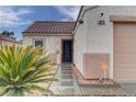 Close up of tan home with terra cotta roof, desert landscaping, and a dark metal front door at 1073 Silver Bullet Ct, Henderson, NV 89011