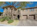 Charming two-story home featuring a combination of stone and stucco exterior, complemented by mature trees and a two-car garage at 2124 Pont National Dr, Henderson, NV 89044