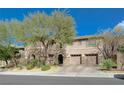 Charming two-story home featuring a combination of stone and stucco exterior, complemented by mature trees and a two-car garage at 2124 Pont National Dr, Henderson, NV 89044