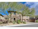 Charming two-story home featuring a combination of stone and stucco exterior, complemented by mature trees and a two-car garage at 2124 Pont National Dr, Henderson, NV 89044