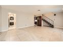 Spacious living room featuring tile flooring, staircase, and access to kitchen and laundry room at 3932 Voxna St, Las Vegas, NV 89119