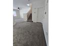 Spacious living room with gray carpet, staircase, and neutral walls at 6460 Raven Hall St, North Las Vegas, NV 89084